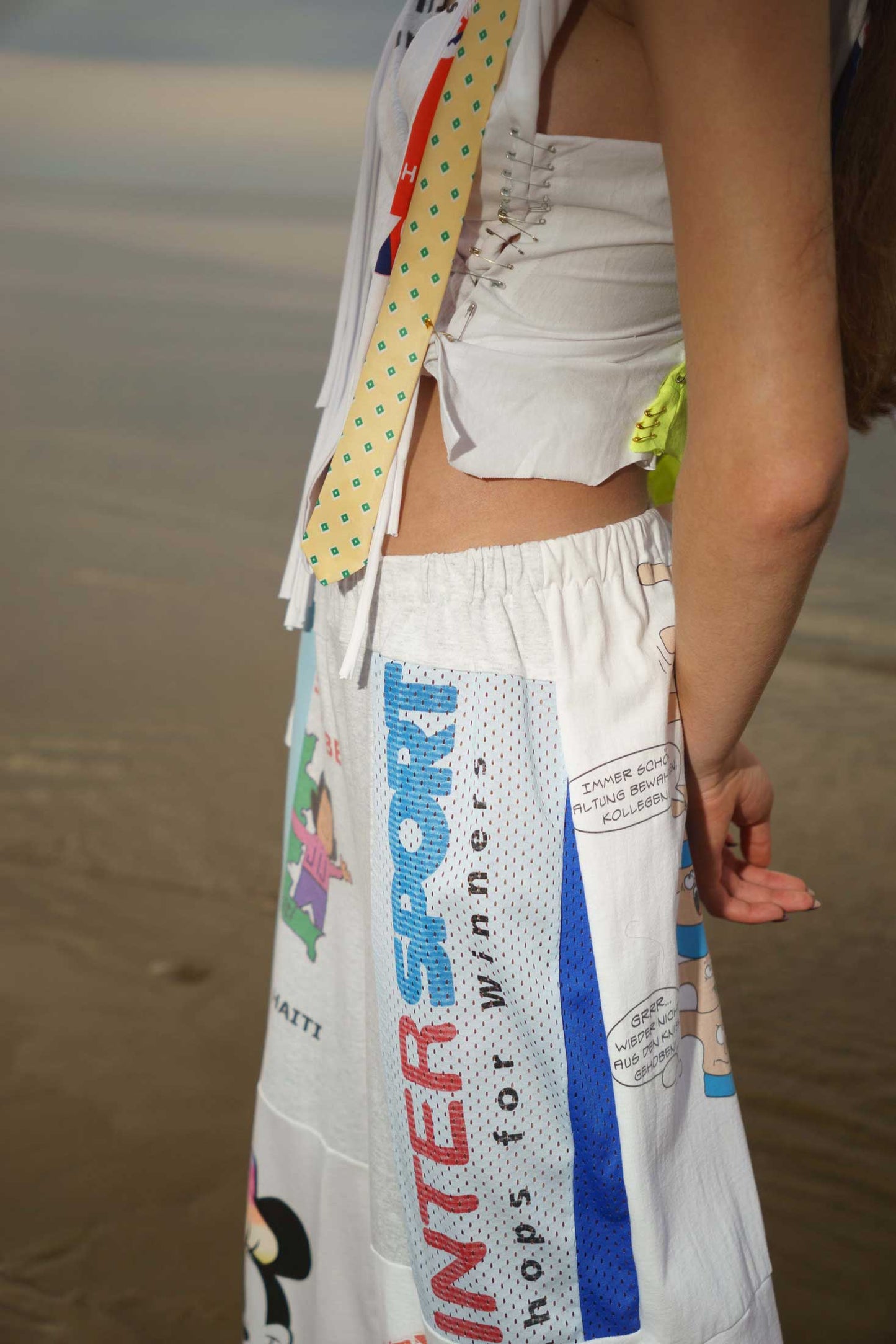 Close-up of white upcycled cotton t-shirt patchwork on wide-leg trousers, handcrafted detail.