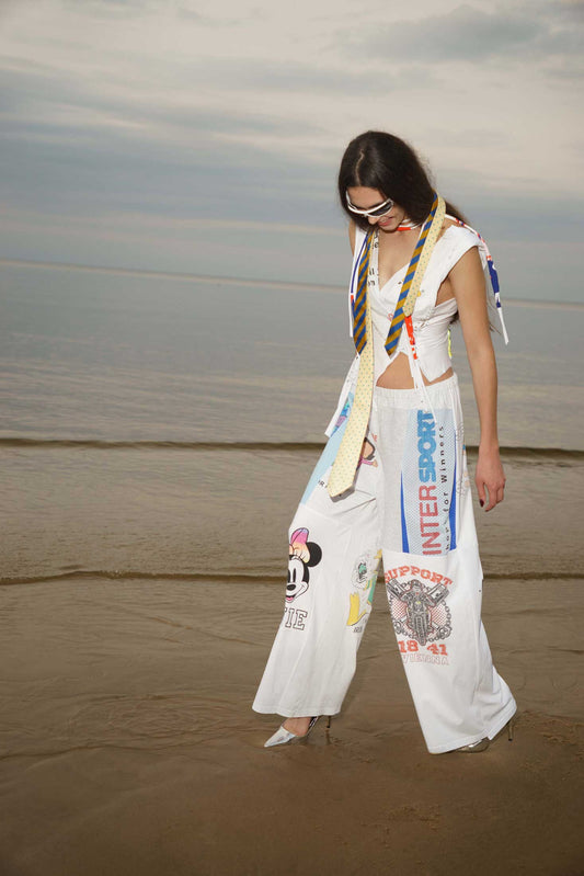 White wide-leg trousers reworked from vintage cotton t-shirts, front view showing patchwork graphics.
