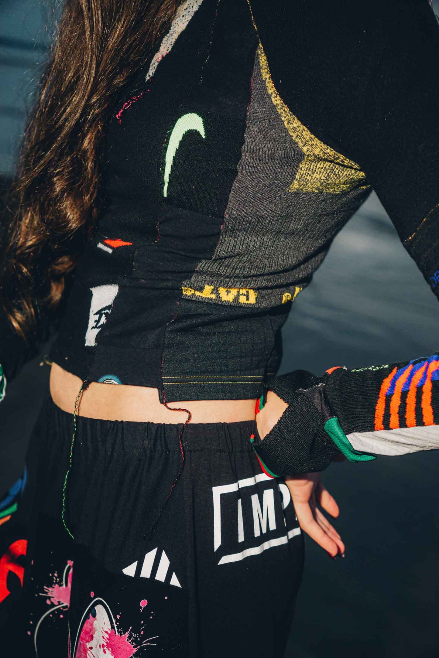 Close-up of graphic cotton t-shirt patchwork detail on black wide-leg trousers.